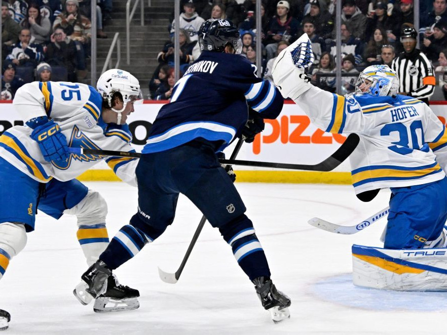 Brankár St. Louis Blues Joel Hofer (30) zasahuje, zatiaľ čo Tyler Tucker (75) bráni proti Vladislavovi Namestnikovovi z Winnipeg Jets.