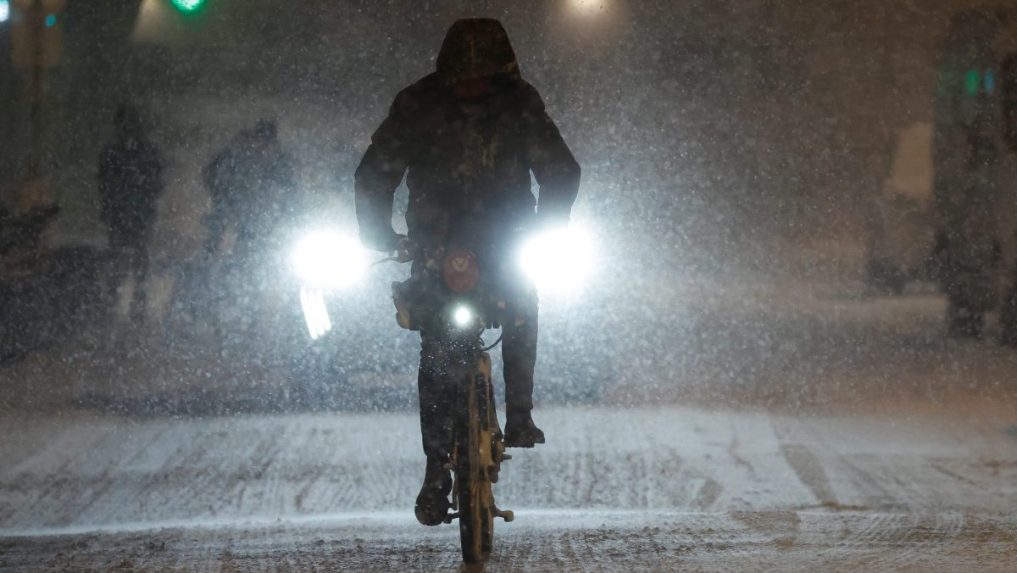 Muž jazdí na bicykli počas sneženia.