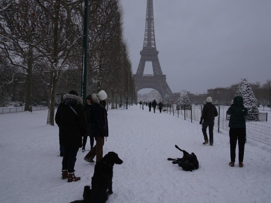 Ľudia venčia svojich psov v zasneženom Paríži.