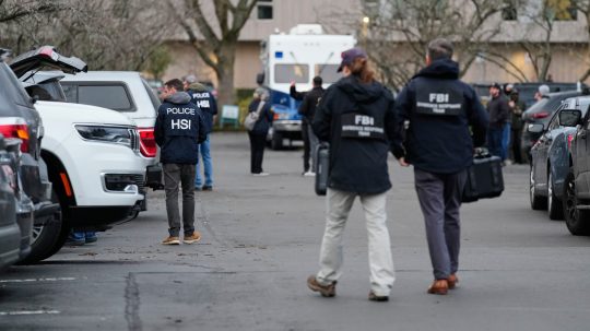 Poškodené auto a približujúci sa pracovníci FBI-