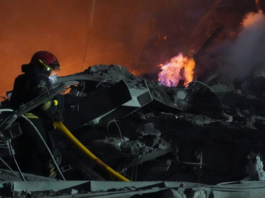 Hasič hasí požiar budovy zničenej po ruskom raketovom útoku v Charkove, na východe Ukrajiny.