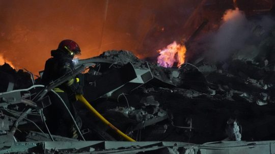 Hasič hasí požiar budovy zničenej po ruskom raketovom útoku v Charkove, na východe Ukrajiny.
