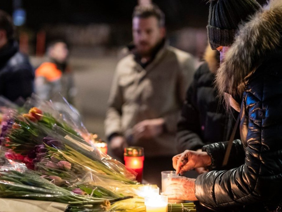 Žena zapaľuje sviečku za obete nočného požiaru v bare vo Švajčiarsku.