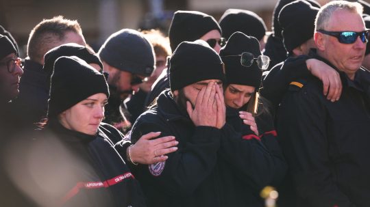 Ľudia smútia za obeťami požiaru.