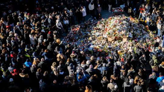 Na snímke ľudia pri pamätníku obetí požiara.