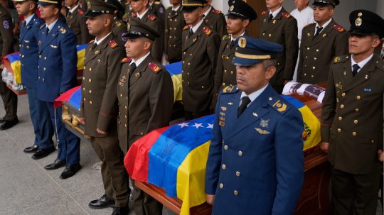 Pohreb vojenských príslušníkov vo Venezuele po útoku USA. Na sníme uniformovaní muži stoja s rakvami prikrytými venezuelskou vlajkou.