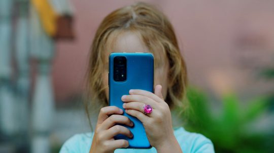 Na snímke dieťa s telefónom.