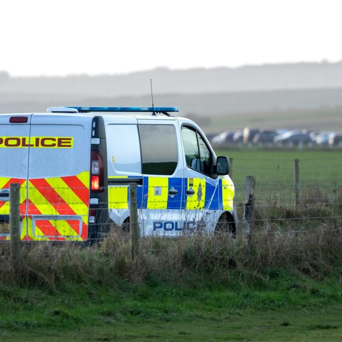 Na snímke je odstavené vozidlo britskej polície, v diaľke kolóna.