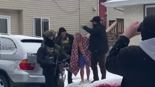 Federálni agenti v USA vyvádzajú muža z domu v spodnej bielizni.