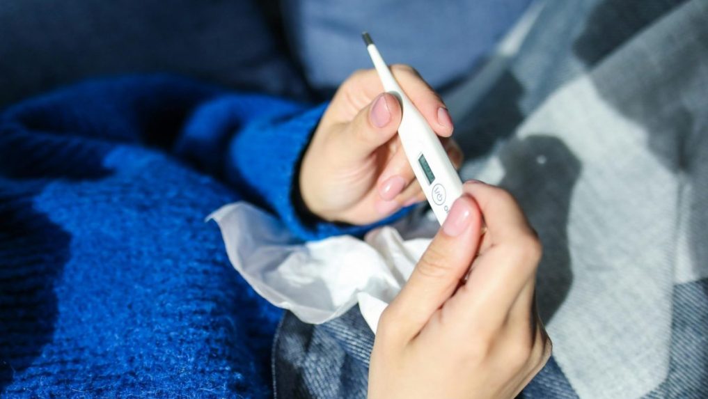 Na ilustračnej snímke osoba s teplomerom v ruke.