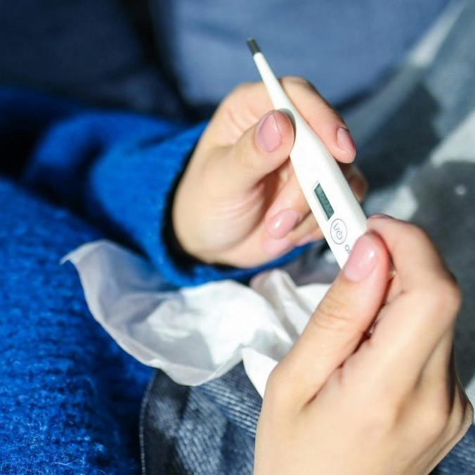 Na ilustračnej snímke osoba s teplomerom v ruke.