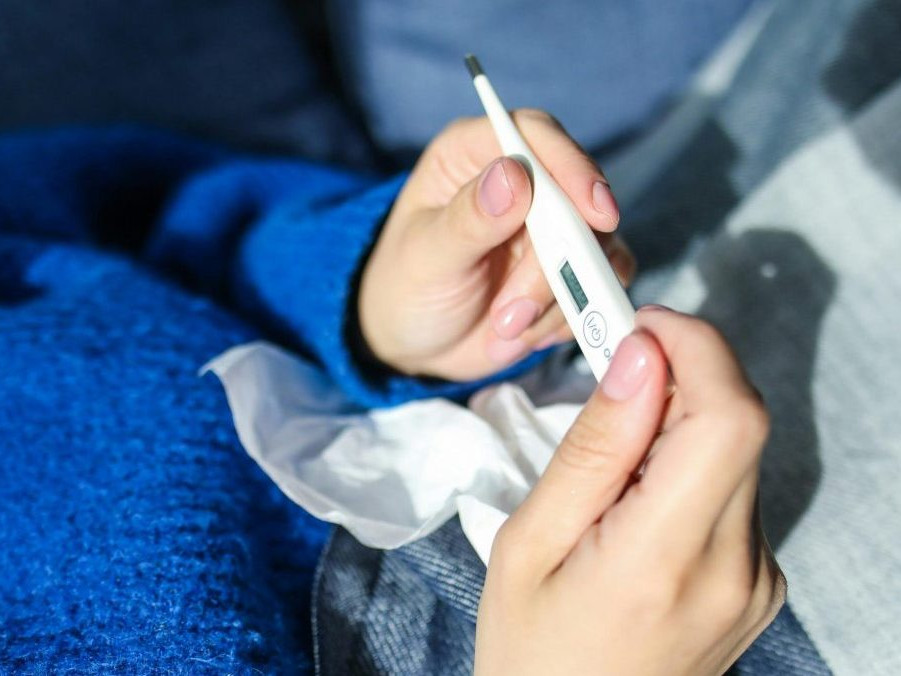 Na ilustračnej snímke osoba s teplomerom v ruke.