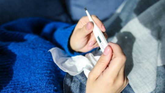 Na ilustračnej snímke osoba s teplomerom v ruke.