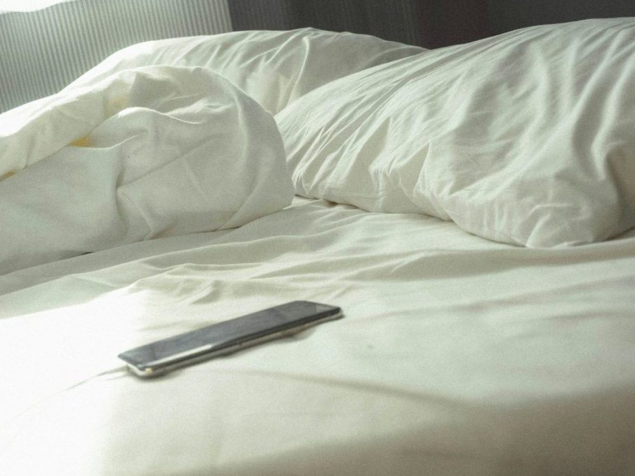 Na snímke telefón položený na posteli.