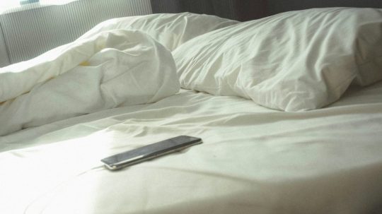 Na snímke telefón položený na posteli.