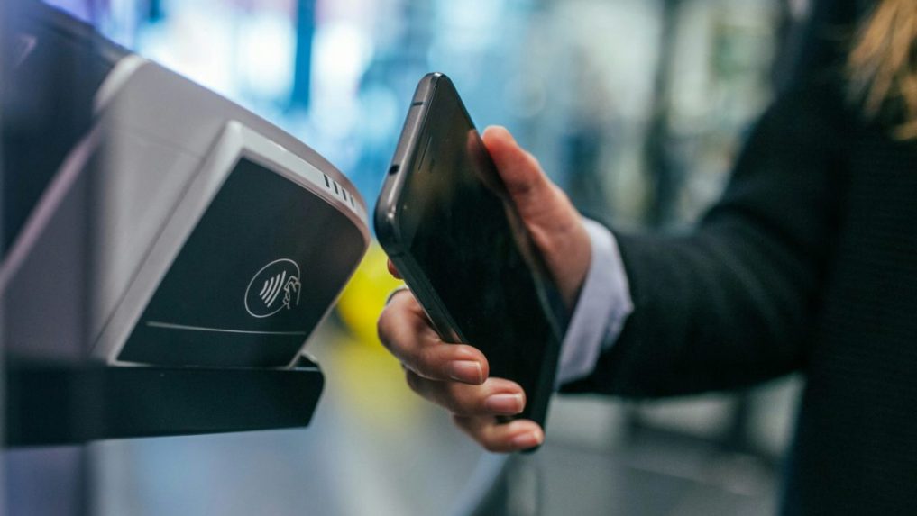Na snímke prikladá žena telefón k terminálu.