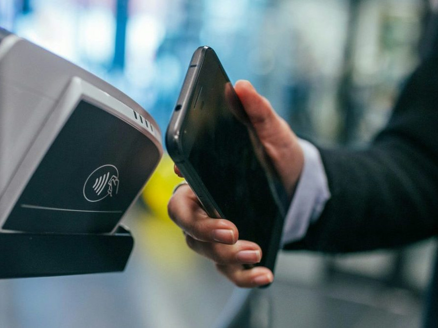 Na snímke prikladá žena telefón k terminálu.