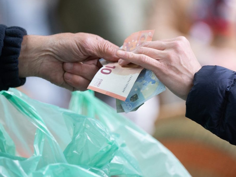 Na ilustračnej snímke osoba podáva peniaze druhej osobe.