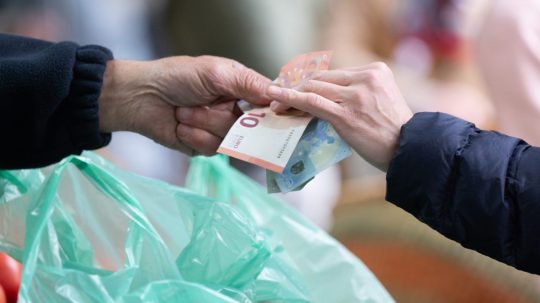 Na ilustračnej snímke osoba podáva peniaze druhej osobe.