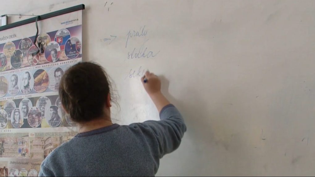 Na ilustračnej snímke učiteľka píše na tabuľu.