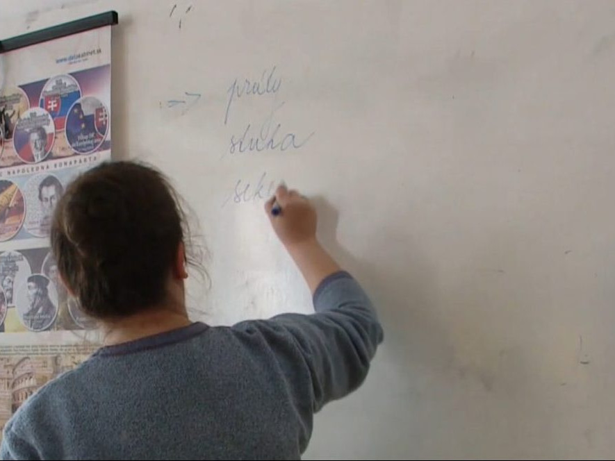 Na ilustračnej snímke učiteľka píše na tabuľu.