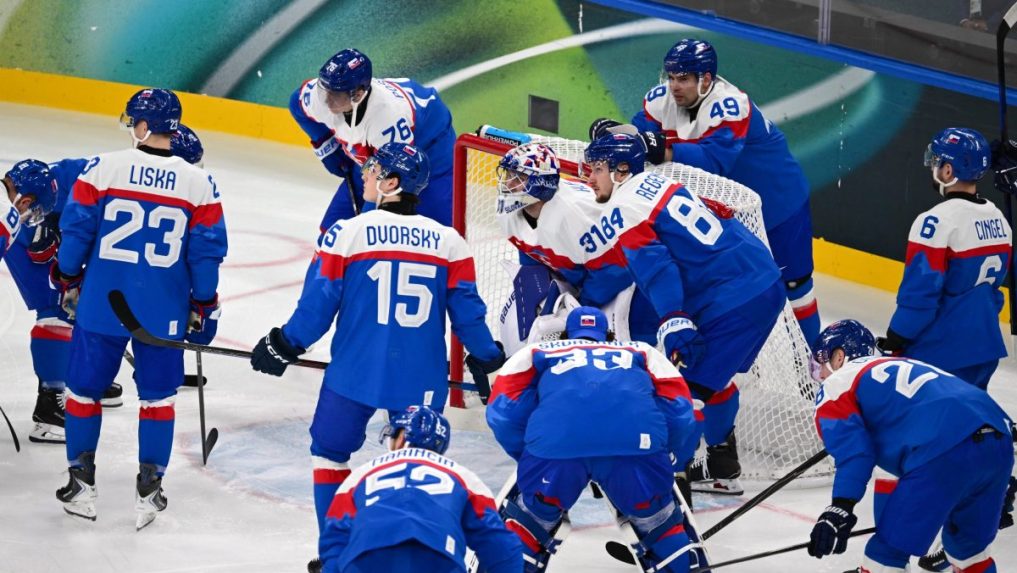 Slovenskí hokejisti stoja pred brankárom Samuelom Hlavajom.