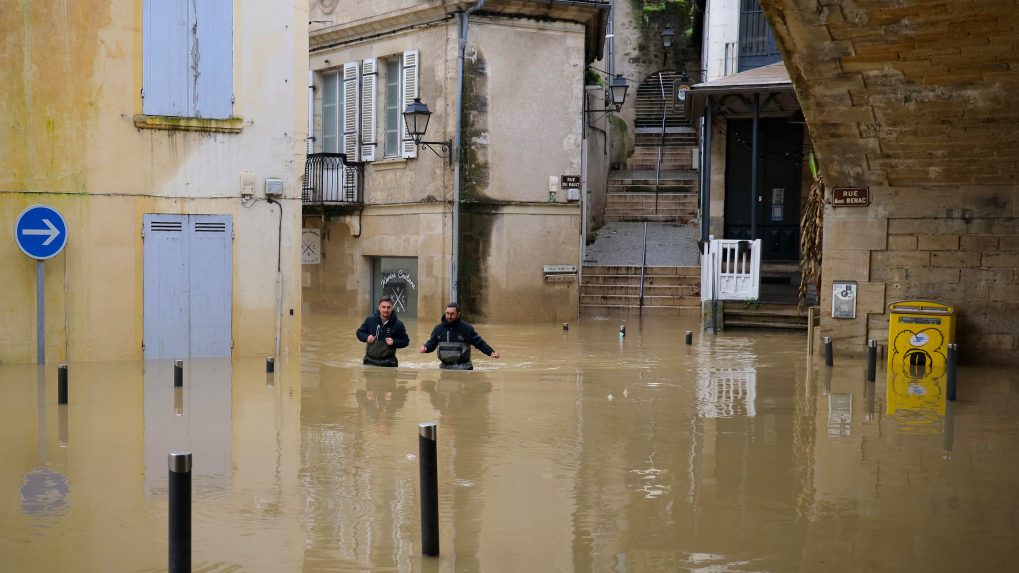 Dvojica mužov sa brodí vysokou vodou v uliciach La Reolle v západnom Francúzsku.