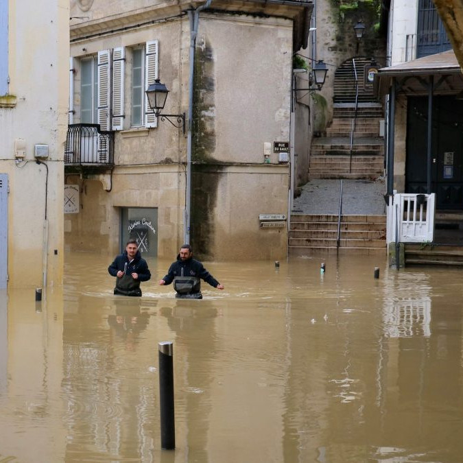 Dvojica mužov sa brodí vysokou vodou v uliciach La Reolle v západnom Francúzsku.