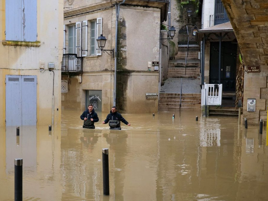 Dvojica mužov sa brodí vysokou vodou v uliciach La Reolle v západnom Francúzsku.