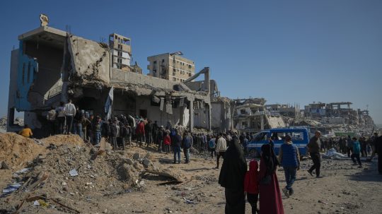 Palestínčania pátrajú po telách v troskách budovy po izraelskom útoku.