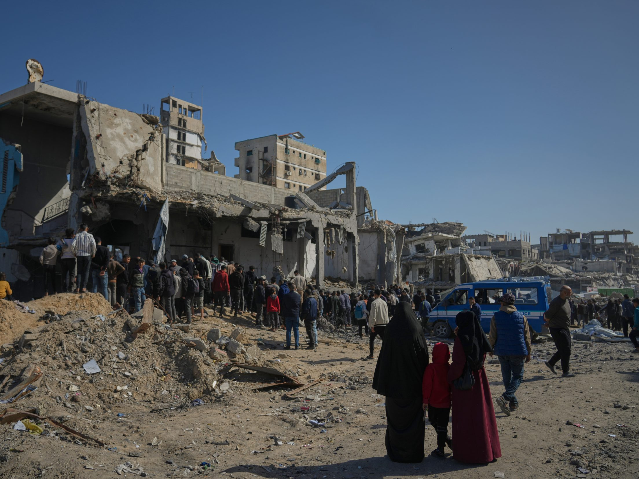 Palestínčania pátrajú po telách v troskách budovy po izraelskom útoku.