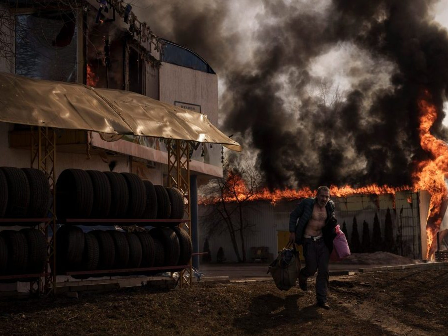 Muž zachraňuje veci z obchodu, ktorý zasiahol požiar po ruskom útoku v ukrajinskom Charkove v piatok 25. marca 2022.
