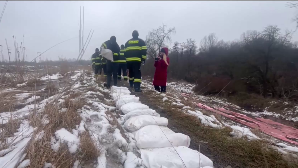 Hasiči umiestňujú na zem vrecia s pieskom.