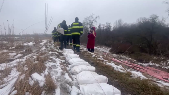 Hasiči umiestňujú na zem vrecia s pieskom.