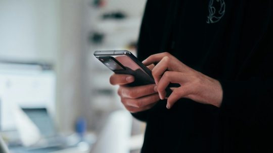 Muž drží v ruke telefón.