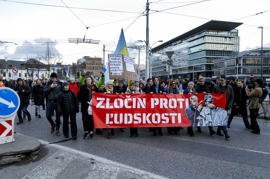 Na snímke ľudia nesú banner "Zločin proti ľudskosti".