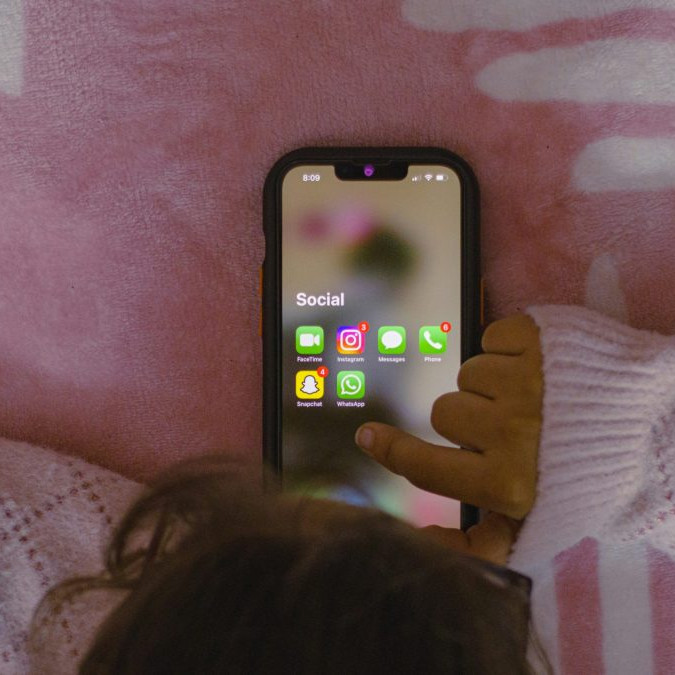 Dieťa na posteli s telefónom.