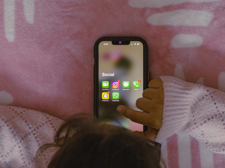 Dieťa na posteli s telefónom.