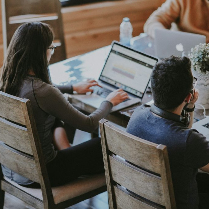 Na snímke sú študenti s laptopmi sediaci za stolom.