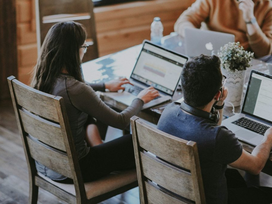 Na snímke sú študenti s laptopmi sediaci za stolom.
