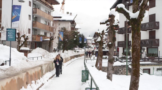 Osoby sa prechádzajú po zasneženom chodníku medzi hotelmi v Taliansku.