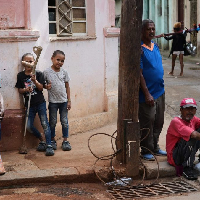 Ľudia sa počas výpadku prúdu v Havane zdržiavajú na chodníku.