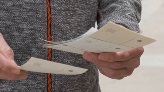 Na snímke drží muž v ruke pohľadnice.