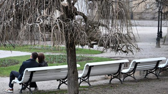 Na ilustračnej snímke pár sediaci na lavičke v parku.