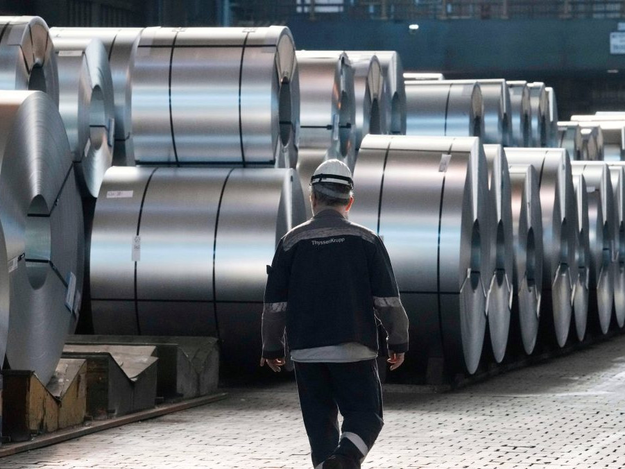 Na ilustračnej snímke oceliar kráča popri oceľových zvitkoch.