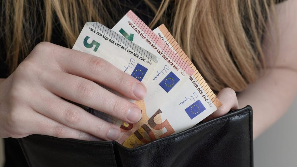 žena vkladá peniaze do peňaženky