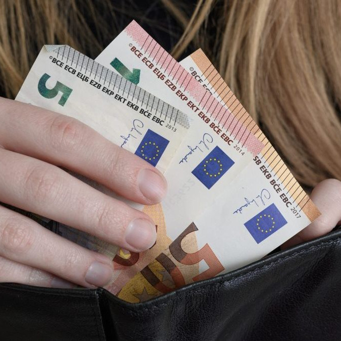 žena vkladá peniaze do peňaženky