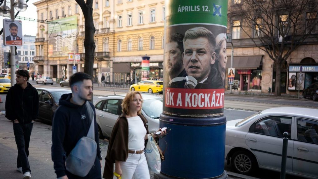 Ľudia prechádzajú okolo plagátu, ktorý propaguje stranu Fidesz.