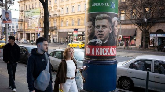 Ľudia prechádzajú okolo plagátu, ktorý propaguje stranu Fidesz.