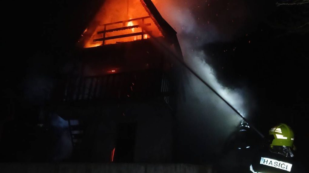 Hasič zasahuje pri požiari chatky.